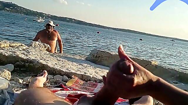 On a nude beach the wife stokes my cock while a voyuer watches
